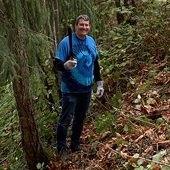 VP John Schuh sporting his Aldrich 50th Anniversary tie-dye tee took a machete to the hillside near the property fence. 