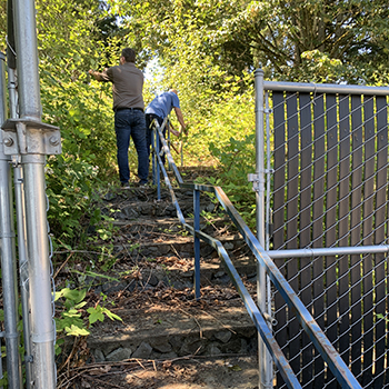 John and Matt had to push aside overgrowth to ascend the stairs to the fields behind ABC on our first site visit to determine project scope.